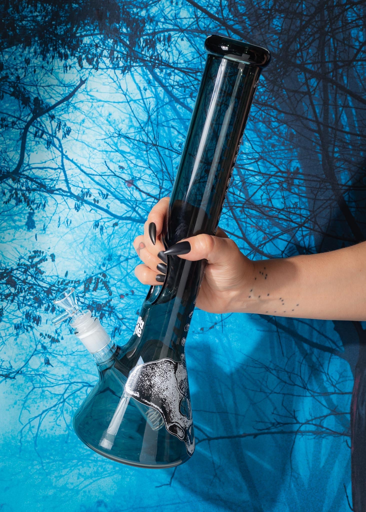 Person holding a black and silver bong against a blue background